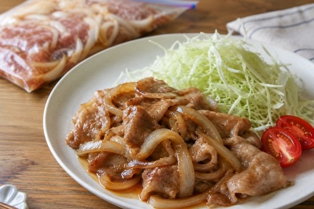 下味冷凍で作った豚の生姜焼きに千切りキャベツとトマトを添えた完成写真