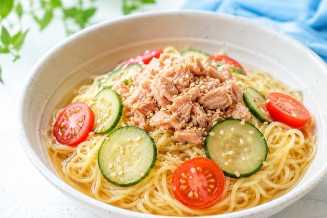 薄黄色のウニそうめんにツナ缶、トマト、きゅうりを盛り付けた冷たい麺料理