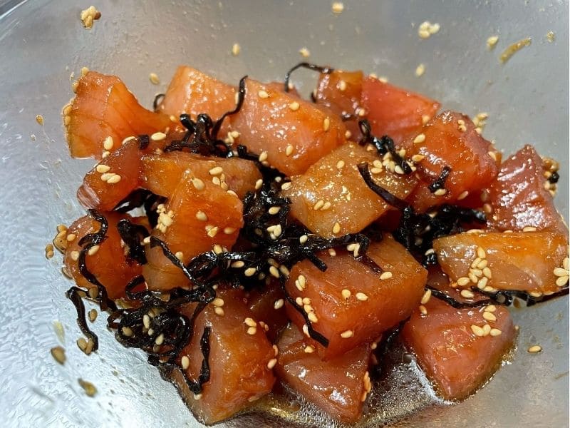 ボウルでマグロと塩昆布、醤油、ごま油、わさび、白ごまを和えている調理工程