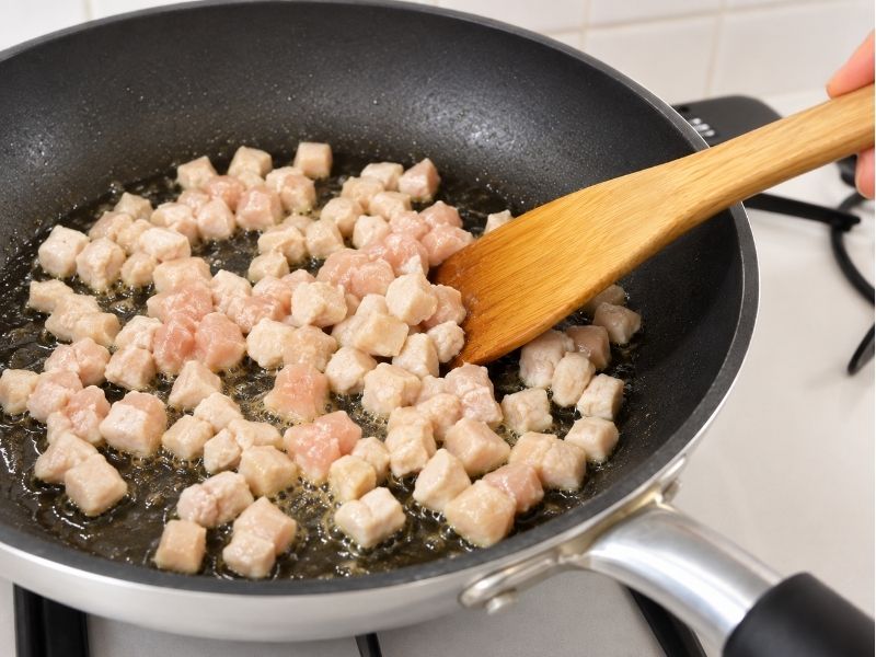 片栗粉を薄くまぶした角切りの鶏むね肉をフライパンで炒めている様子