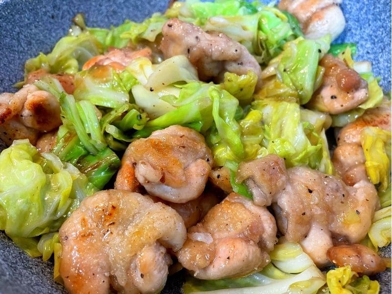 焼き色を付けた鶏肩肉とキャベツをフライパンで炒め合わせている様子