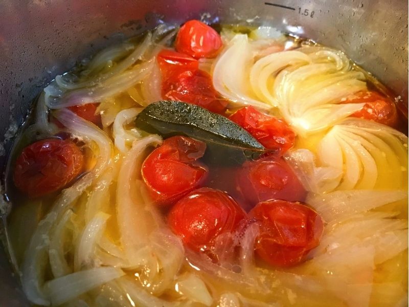 圧力鍋でミニトマトと玉ねぎをコンソメスープで煮込んでいる様子